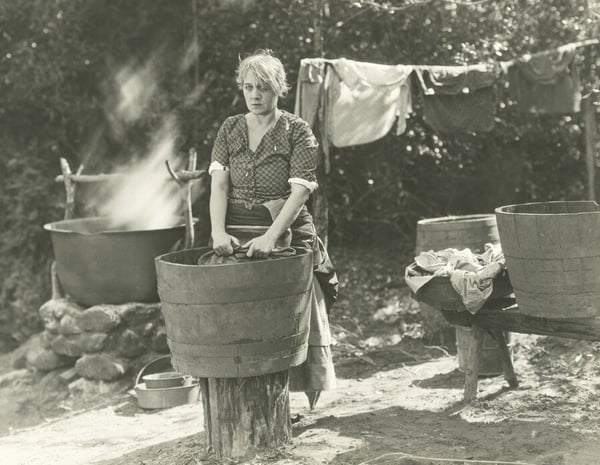 eine Frau wäscht ihre Wäsche von Hand vor 100 Jahren