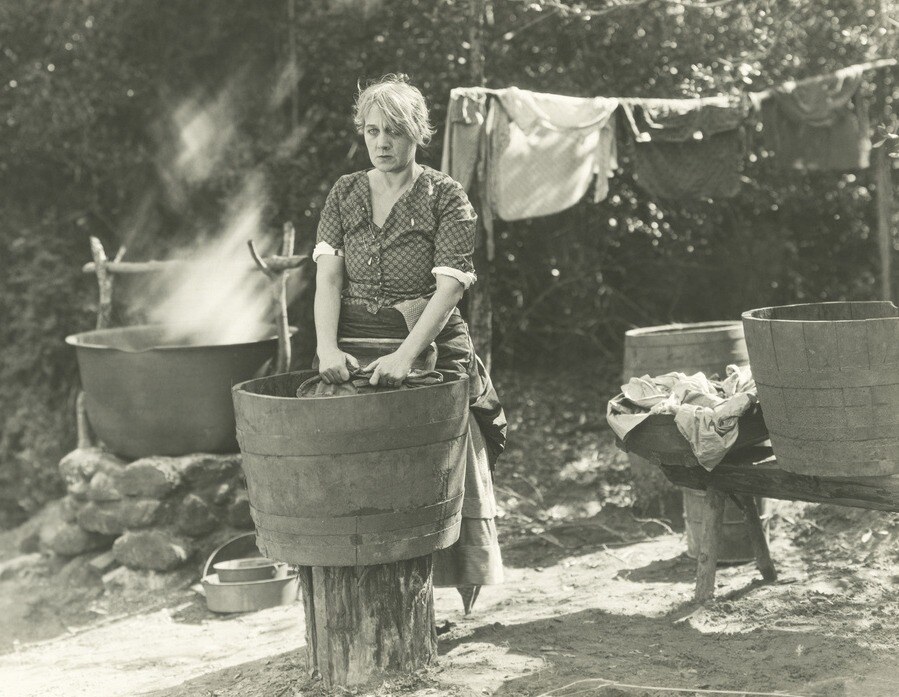 eine Frau wäscht ihre Wäsche von Hand vor 100 Jahren
